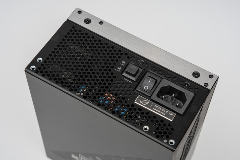 Tipični saćasti uzorak s vanjske strane napajanja prekinut je uobičajenim IEC konektorom, gumbićem za uključenje, ali i neuobičajenim gumbom Turbo te ROG-ovom značkom