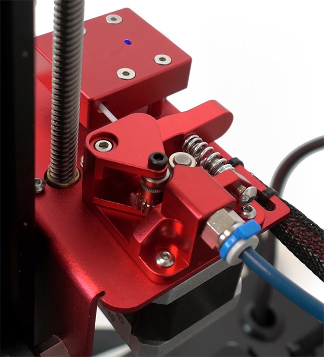 Detektor filamenta i ekstruder sada su smješteni na integralno aluminijsko postolje, a ekstruder koristi rješenje s dva zupčasta vijka koje praktično onemogućava proklizavanje filamenta. Bowden cijev je Capricorn Teflon, vrlo precizna i glatka. 
