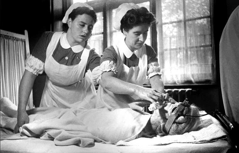 Dokumentarna fotografija pripremanja psihijatrijskog pacijenta za moždane elektrošokove tijekom 1940-ih godina u Velikoj Britaniji. Lijevo (ili desno?): nurse Ratched