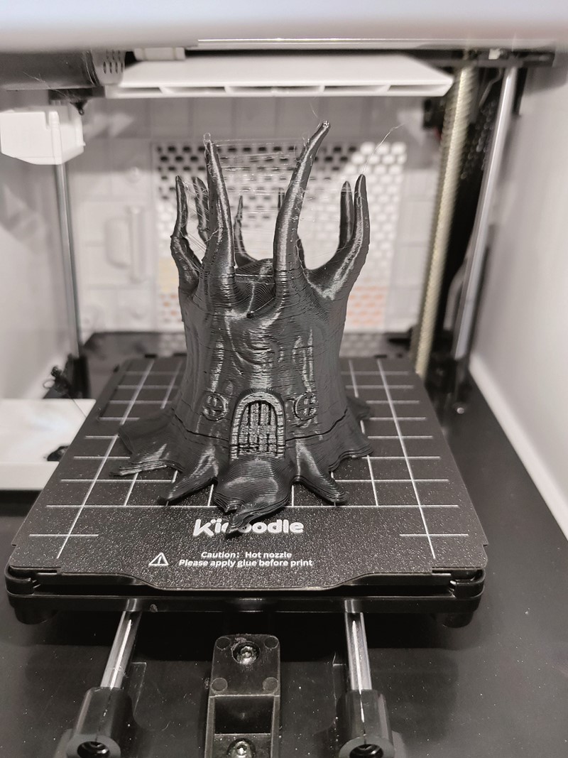 Kako pisač automatski zaustavlja ispis i hladi glavu čim se otvore vrata komore, naša dva otvaranja rezultirala su dvama jasno vidljivim horizontalnim crtama u ispisu. Stringing na vrhu posljedica je vrlo visoke temperature  (za PLA) taljevine koja je potrebna zbog velike brzine ispisa